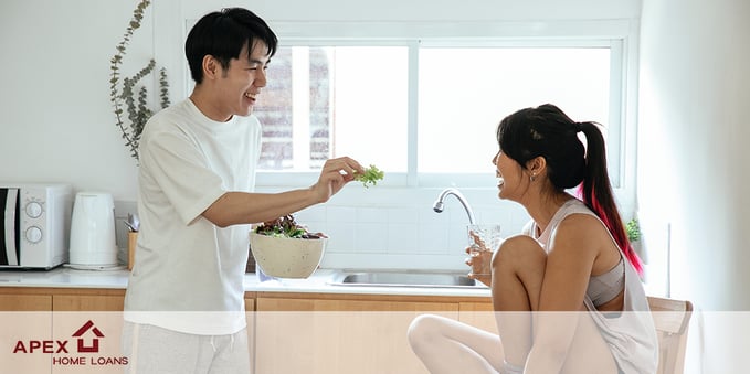 A young couple sharing a salad in their newly bought home.